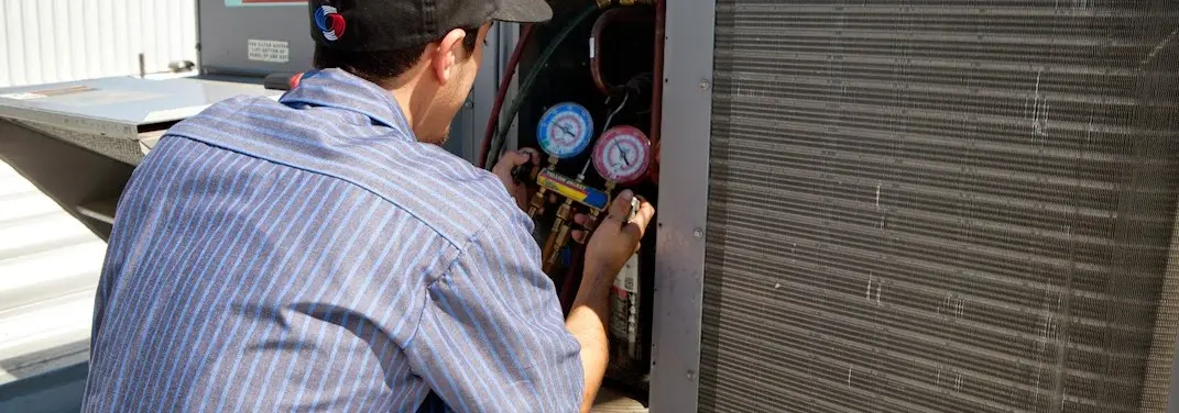 HVAC technician servicing a condenser unit in East Greenwich
