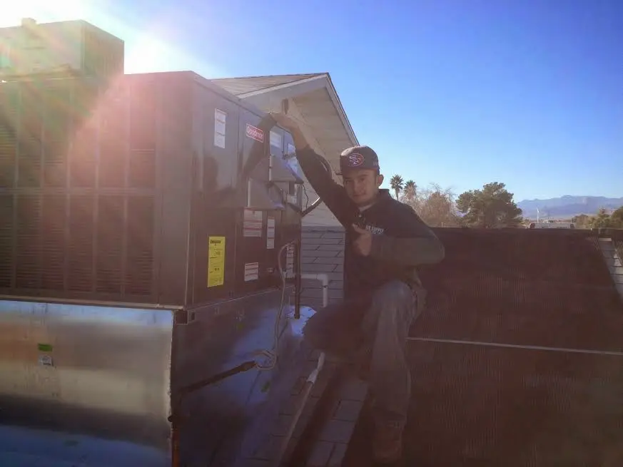 HVAC technician performing AC Tune-Up on a rooftop unit in East Greenwich